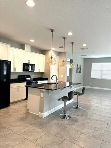 a kitchen with granite countertop a stove a sink and a refrigerator