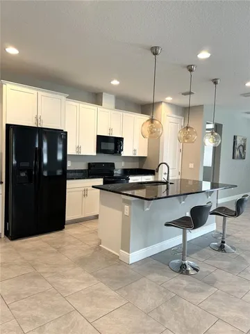 a kitchen with stainless steel appliances kitchen island granite countertop a refrigerator and a sink