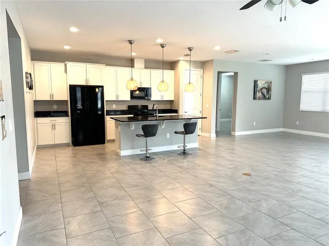 a view of kitchen with stainless steel appliances kitchen island granite countertop a refrigerator and cabinets