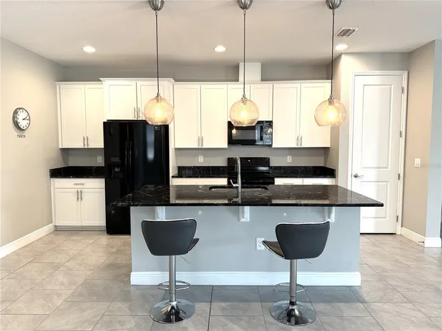 a kitchen with stainless steel appliances kitchen island granite countertop a refrigerator a stove a sink and a wooden cabinets