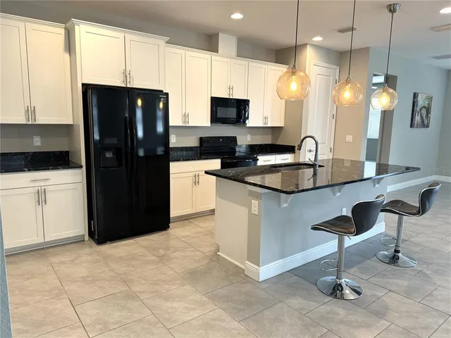 a kitchen with stainless steel appliances granite countertop a refrigerator a sink a stove a dining table and chairs