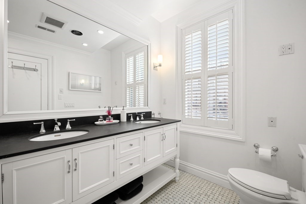 212 West Springfield Street, Unit 2 Boston, MA 02118 - Photo 22 of 41 a bathroom with a granite countertop sink a toilet a mirror and a window