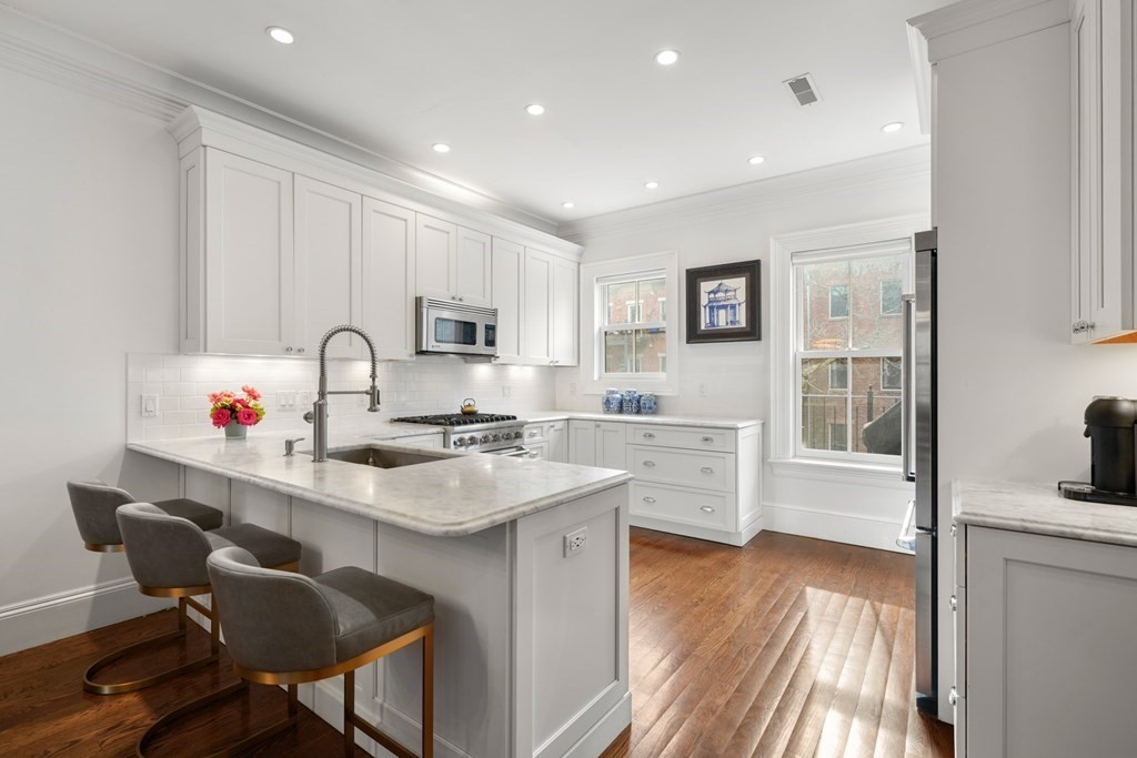 212 West Springfield Street, Unit 2 Boston, MA 02118 - Photo 8 of 41 a kitchen with stainless steel appliances granite countertop a sink dishwasher a stove a dining table and chairs with wooden floor