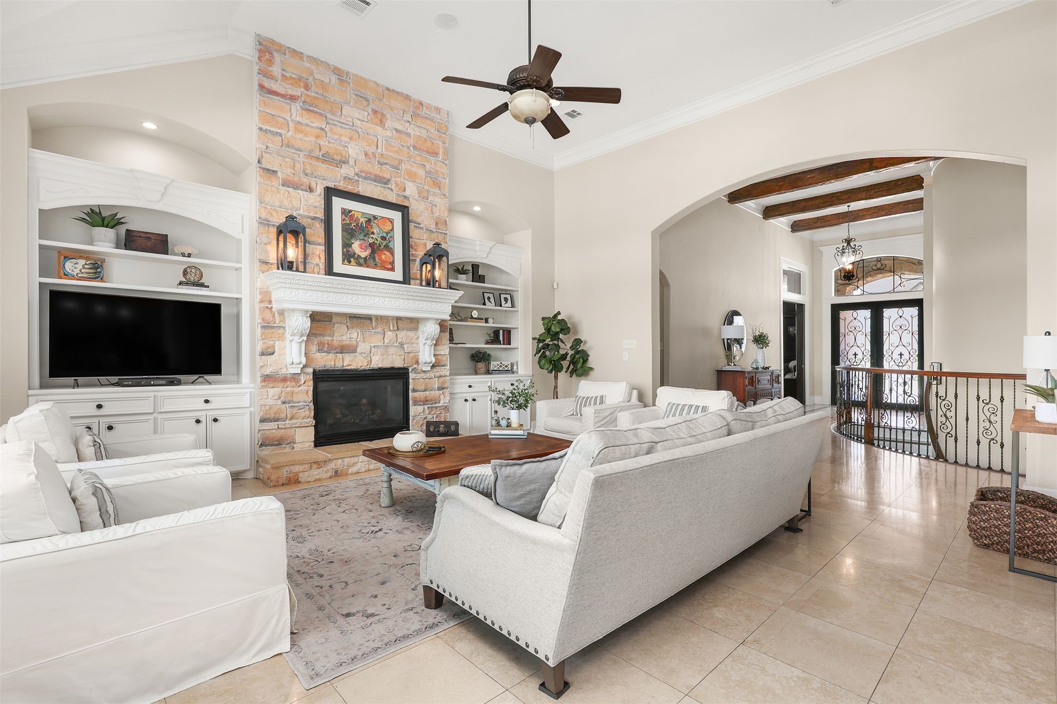 10896 Decatur Street Willis, TX 77318 - Photo 24 of 50 Experience the perfect blend of elegance and comfort in this living room, featuring a cozy stone fireplace, built-in shelving, and graceful archways, all bathed in natural light from large windows and enhanced by high ceilings and a neutral palette—ideal for both entertaining and relaxing.