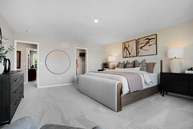 a spacious bedroom with a bed a mirror with dresser and mirror