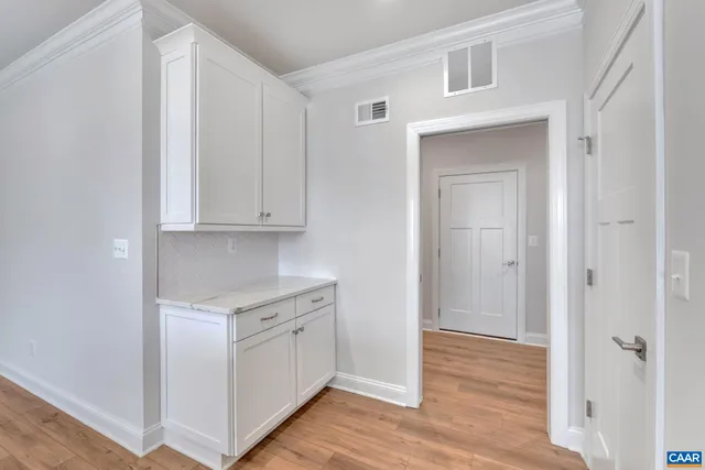 a view of a kitchen with white cabinets and wooden floor