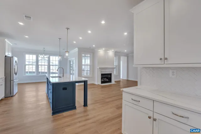 a open kitchen with stainless steel appliances granite countertop a refrigerator a sink dishwasher and a fireplace with wooden floor