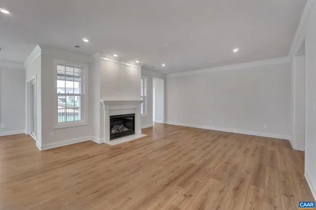 an empty room with wooden floor fireplace and windows