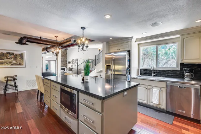 a kitchen with stainless steel appliances granite countertop a sink a stove and a wooden floors