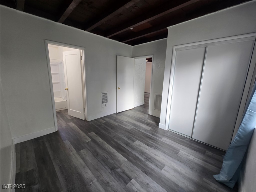 432 North 15th Street, Unit B Las Vegas, NV 89101 - Photo 7 of 9 Unfurnished bedroom featuring beam ceiling, dark wood-style flooring, a closet, heating unit, and connected bathroom