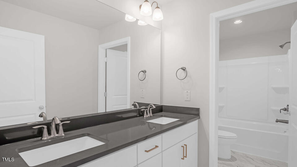 176 Red Jasper Way Clayton, NC 27520 - Photo 21 of 35 a bathroom with a granite countertop sink a large mirror and a bathtub