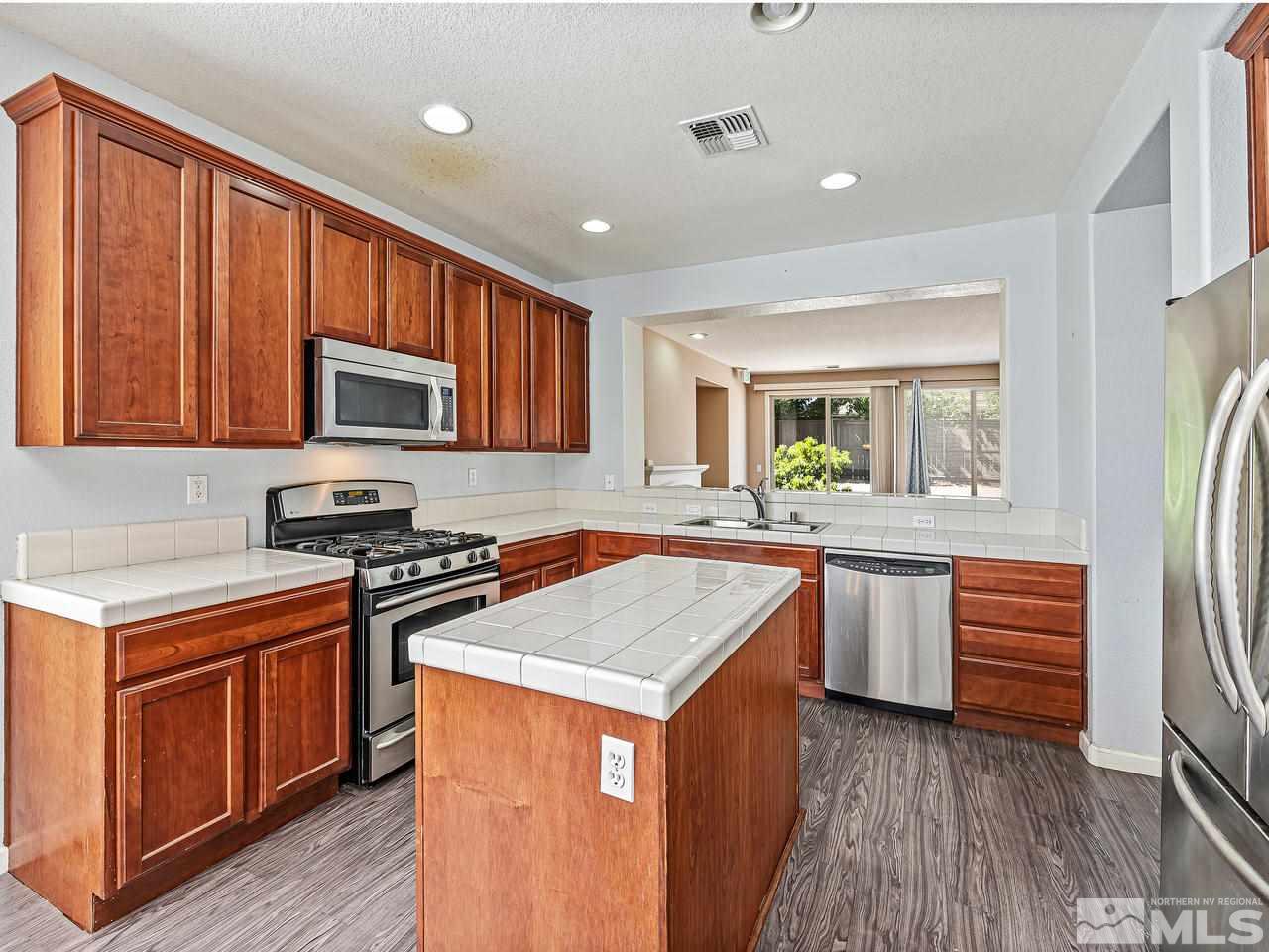 404 Sysonby Court Reno, NV 89521 - Photo 11 of 25 a kitchen with stainless steel appliances granite countertop a stove a sink dishwasher and a refrigerator with wooden floor