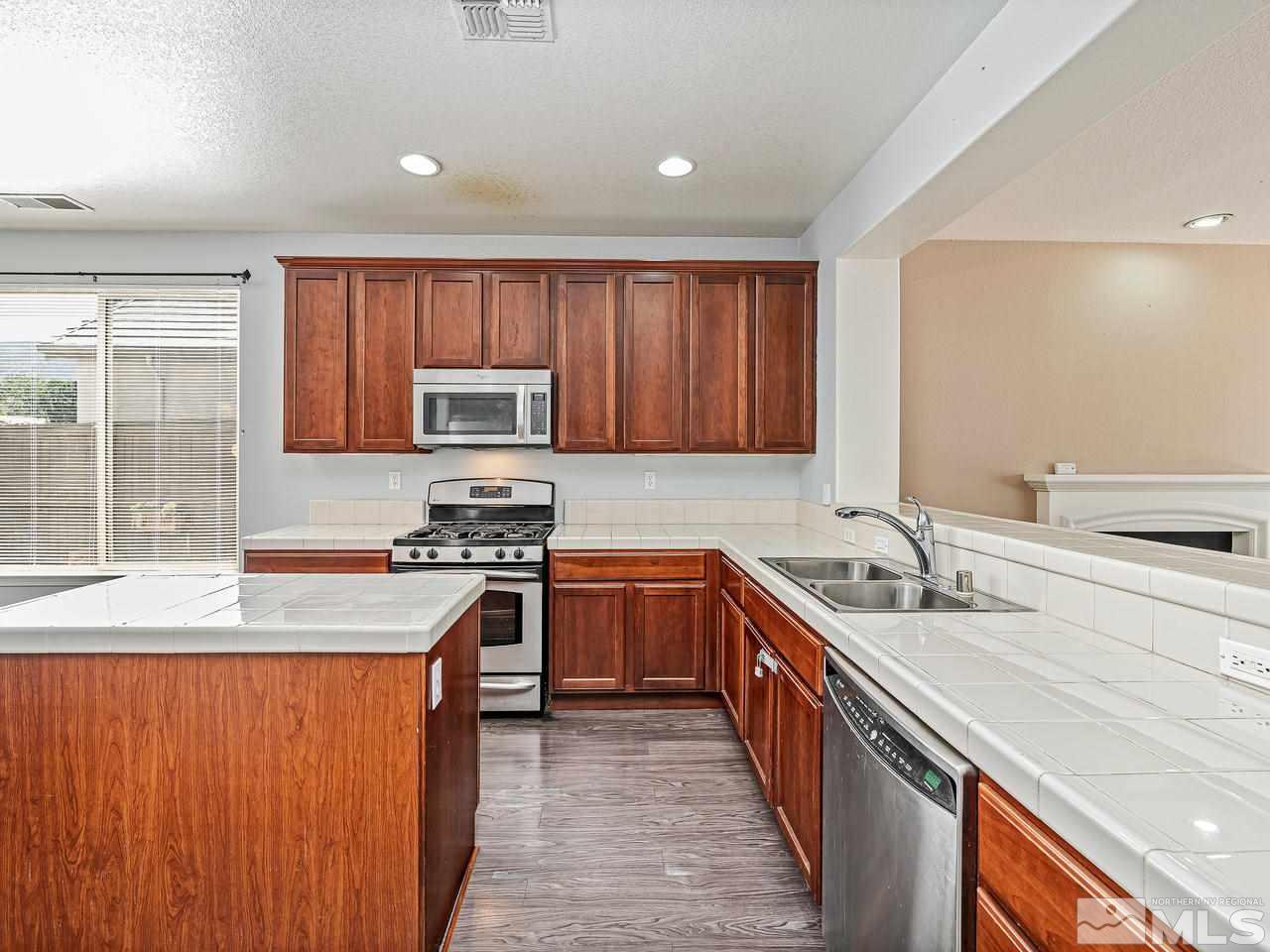 404 Sysonby Court Reno, NV 89521 - Photo 10 of 25 a kitchen with stainless steel appliances granite countertop wooden cabinets a sink and a stove