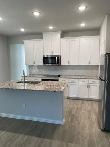 a kitchen with stainless steel appliances granite countertop a stove a sink and a microwave