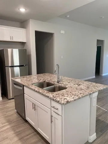 a kitchen with stainless steel appliances granite countertop a sink and a refrigerator