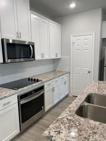 a kitchen with granite countertop a sink and stainless steel appliances
