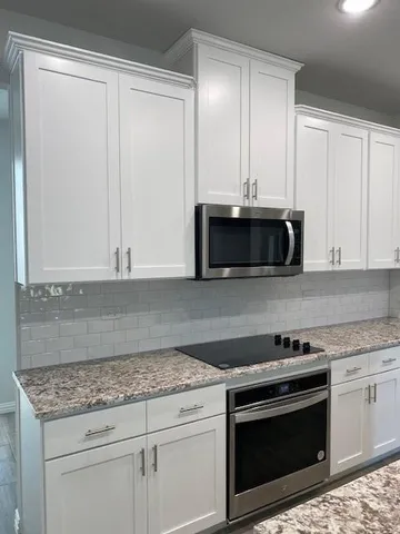 a kitchen with granite countertop white cabinets and stainless steel appliances