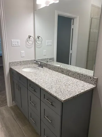 a bathroom with a granite countertop sink and a mirror