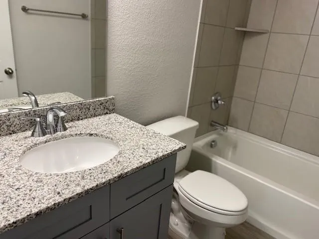 a bathroom with a granite countertop sink toilet and shower