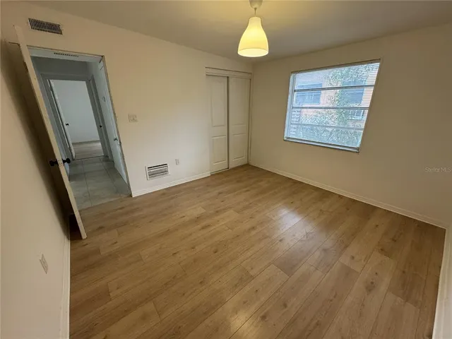 an empty room with wooden floor and windows