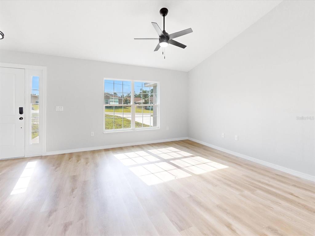 16619 Southwest 31st Circle Ocala, FL 34473 - Photo 5 of 26 an empty room with wooden floor chandelier fan and windows