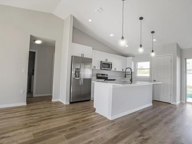 a kitchen with stainless steel appliances kitchen island wooden floors stove and white cabinets