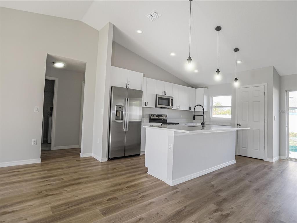 16619 Southwest 31st Circle Ocala, FL 34473 - Photo 6 of 26 a kitchen with stainless steel appliances kitchen island wooden floors stove and white cabinets