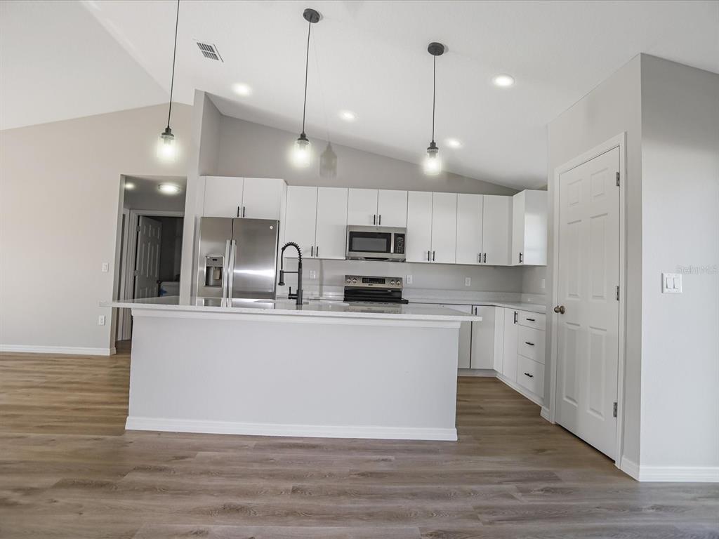 16619 Southwest 31st Circle Ocala, FL 34473 - Photo 7 of 26 a kitchen with stainless steel appliances granite countertop a sink a stove a refrigerator and white cabinets with wooden floor