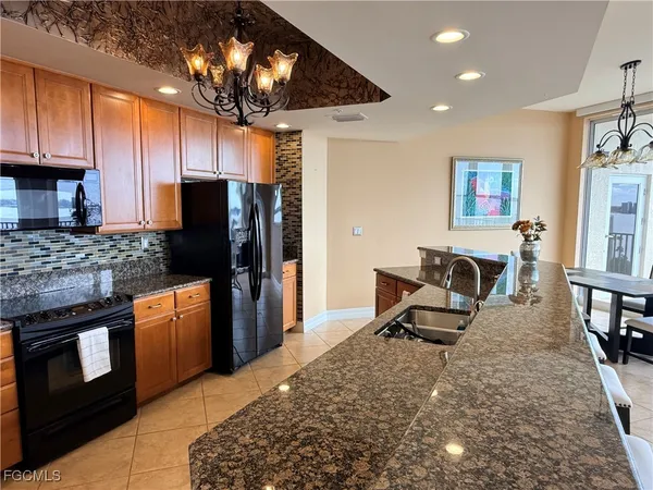 a kitchen with stainless steel appliances kitchen island granite countertop a refrigerator stove top oven and sink