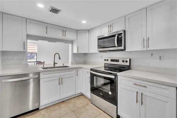 a kitchen with white cabinets stainless steel appliances and sink