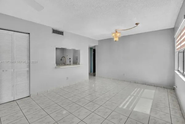 a view of an empty room with window and chandelier fan