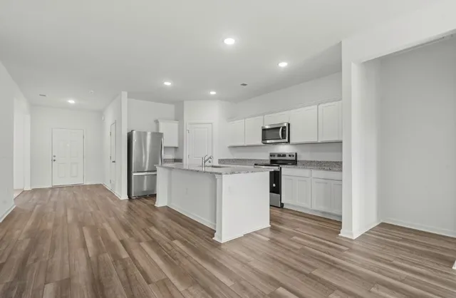 a kitchen with white cabinets stainless steel appliances and wooden floor