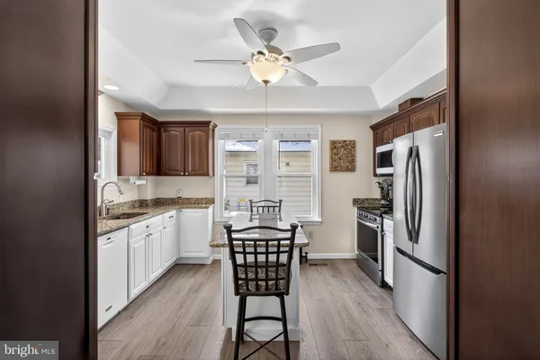 a kitchen with stainless steel appliances granite countertop a refrigerator a stove a sink dishwasher a dining table and chairs with wooden floor