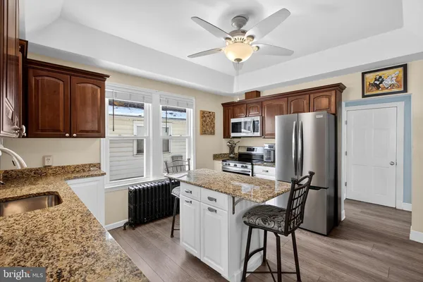 a kitchen with stainless steel appliances granite countertop a refrigerator a sink dishwasher a stove with wooden cabinets and wooden floor