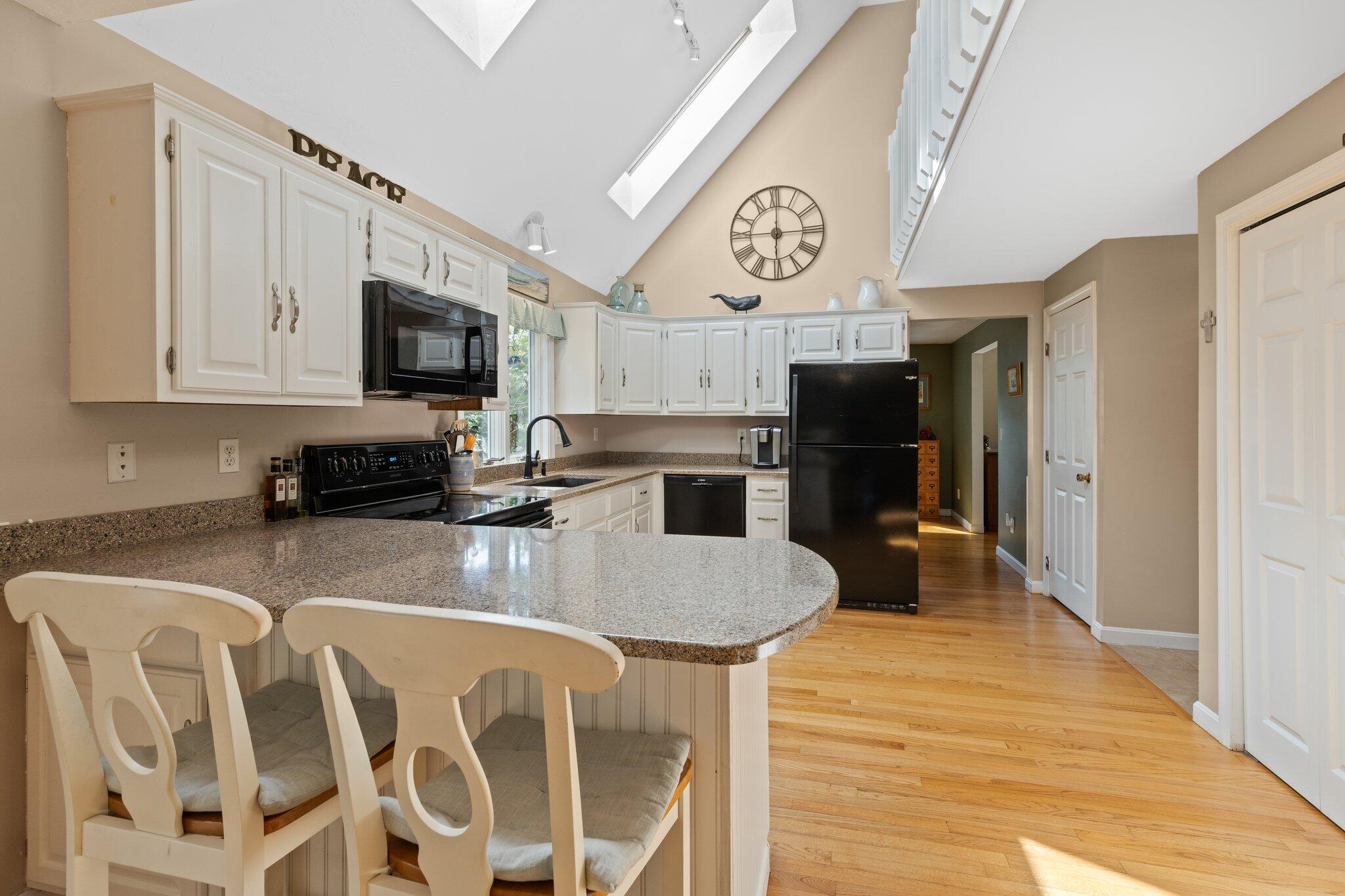 131 Clamshell Cove Road Cotuit, MA 02635 - Photo 13 of 67 a kitchen with stainless steel appliances granite countertop a refrigerator a stove top oven a sink dishwasher and white cabinets with wooden floor