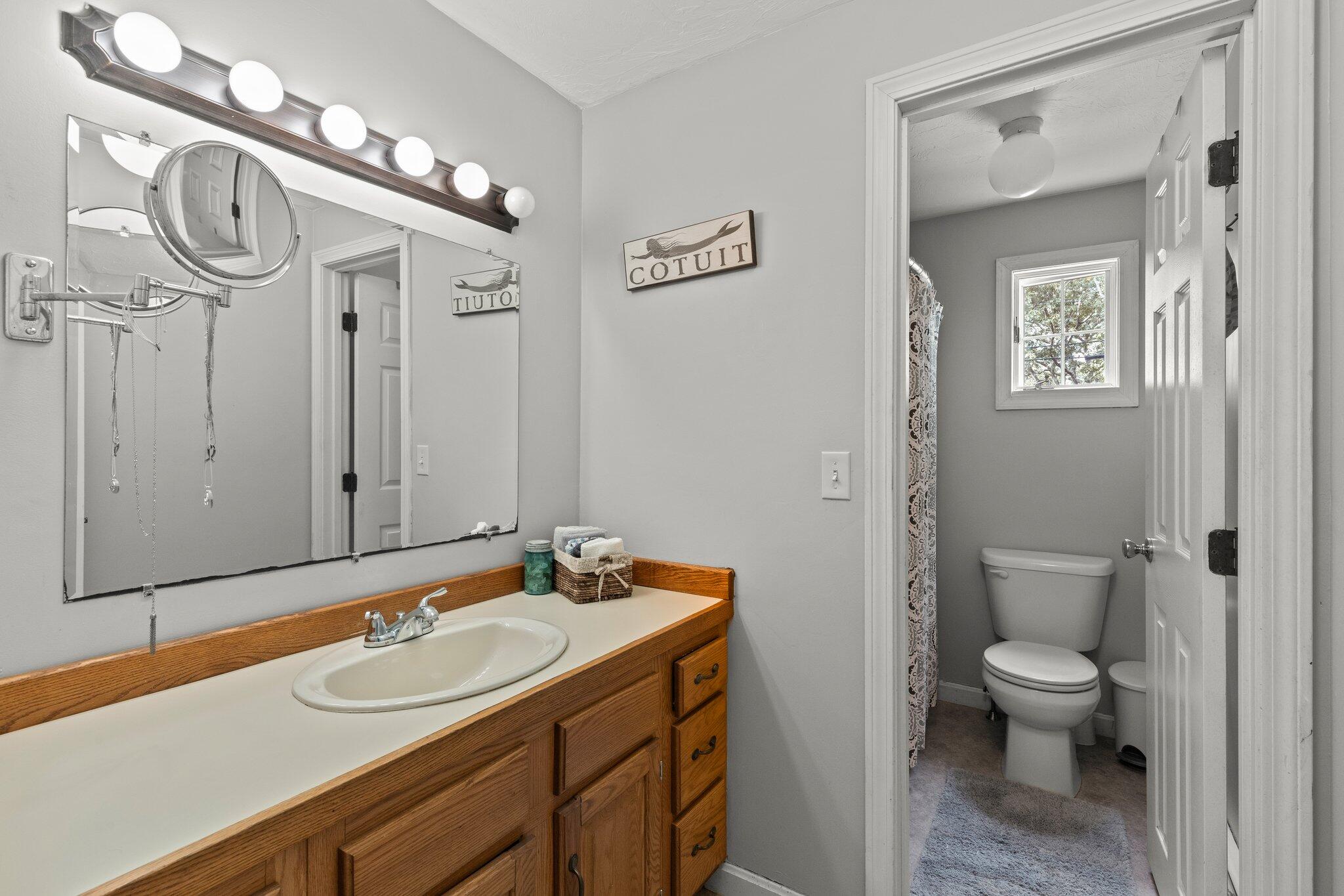 131 Clamshell Cove Road Cotuit, MA 02635 - Photo 32 of 67 a bathroom with a sink a toilet and a mirror