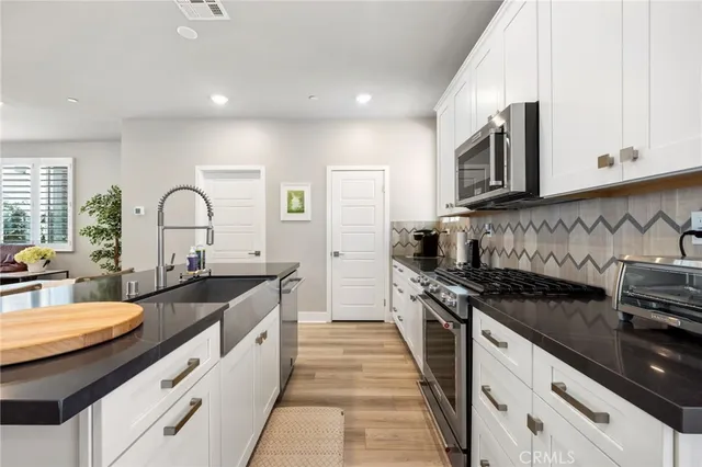 a kitchen with granite countertop white cabinets and stainless steel appliances