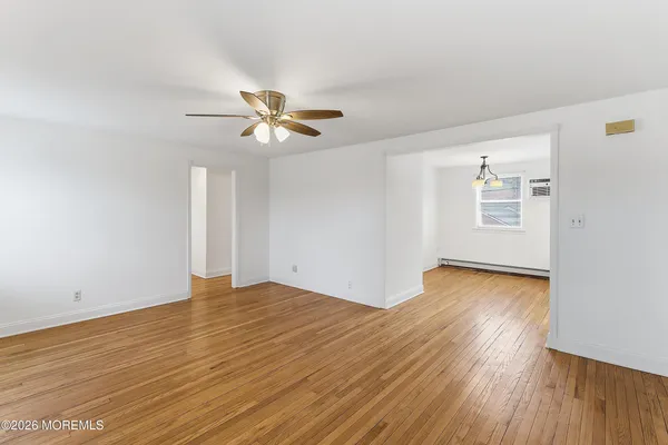 a view of an empty room with window and wooden floor