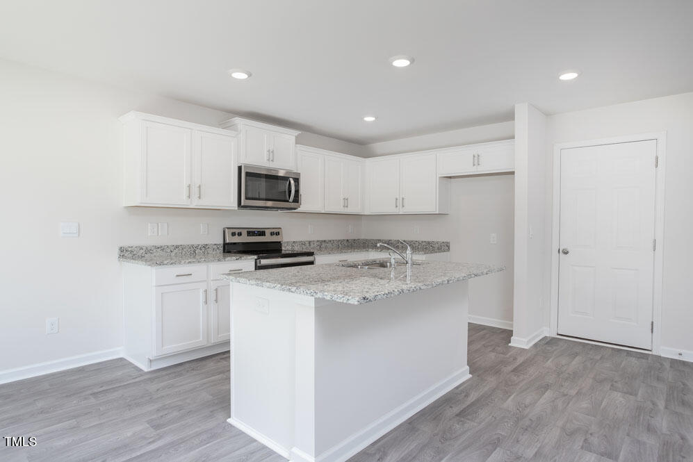 6048 Sodium Street Raleigh, NC 27610 - Photo 12 of 30 a kitchen with stainless steel appliances granite countertop a stove top oven a sink a refrigerator and white cabinets