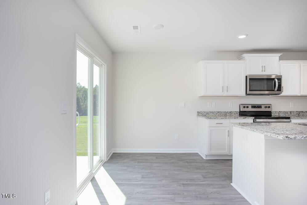 6048 Sodium Street Raleigh, NC 27610 - Photo 10 of 30 a kitchen with granite countertop a stove a sink and a microwave