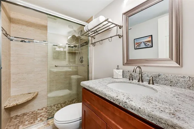a bathroom with a granite countertop sink toilet and shower