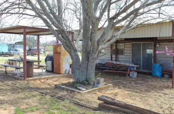 a view of a backyard with a table and chairs under a large tree