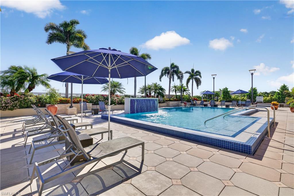 9115 Strada Place, Unit 5504 Naples, FL 34108 - Photo 18 of 22 a view of patio with chairs and table under an umbrella with a barbeque