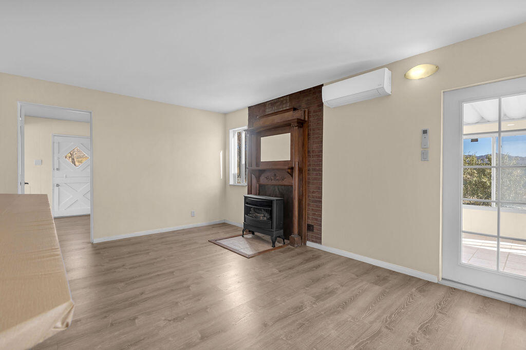 51088 Mecca Road Morongo Valley, CA 92256 - Photo 29 of 77 an empty room with wooden floor fireplace and windows