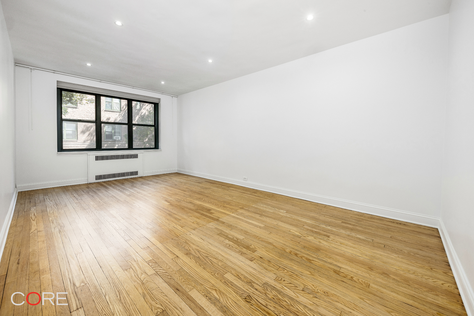 34-21 78th Street, Unit 2B Queens, NY 11372 - Photo 1 of 9 an empty room with wooden floor and windows