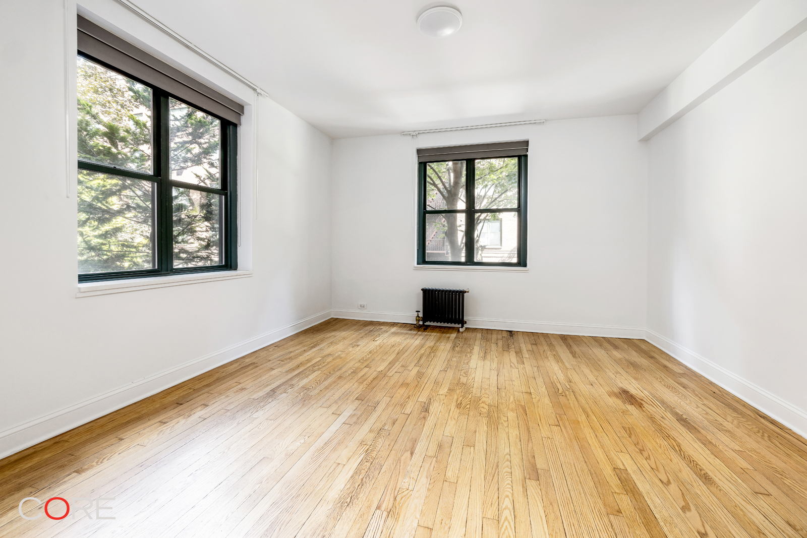 34-21 78th Street, Unit 2B Queens, NY 11372 - Photo 4 of 9 an empty room with wooden floor and windows