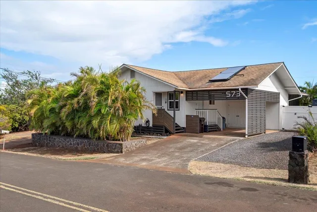 a front view of a house with a garden and parking