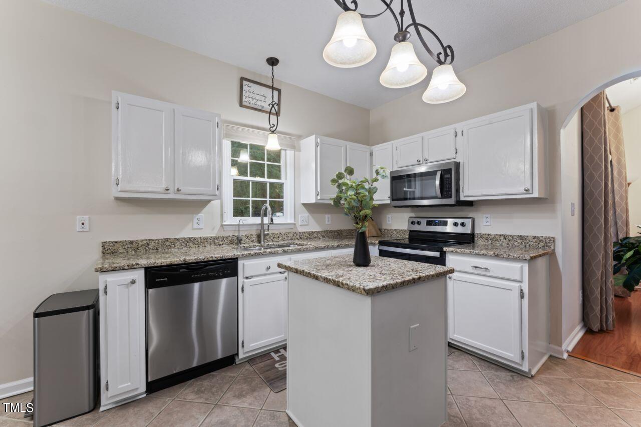 12129 Mabledon Court Raleigh, NC 27613 - Photo 13 of 31 a kitchen with stainless steel appliances granite countertop a sink a stove a refrigerator cabinets and chairs