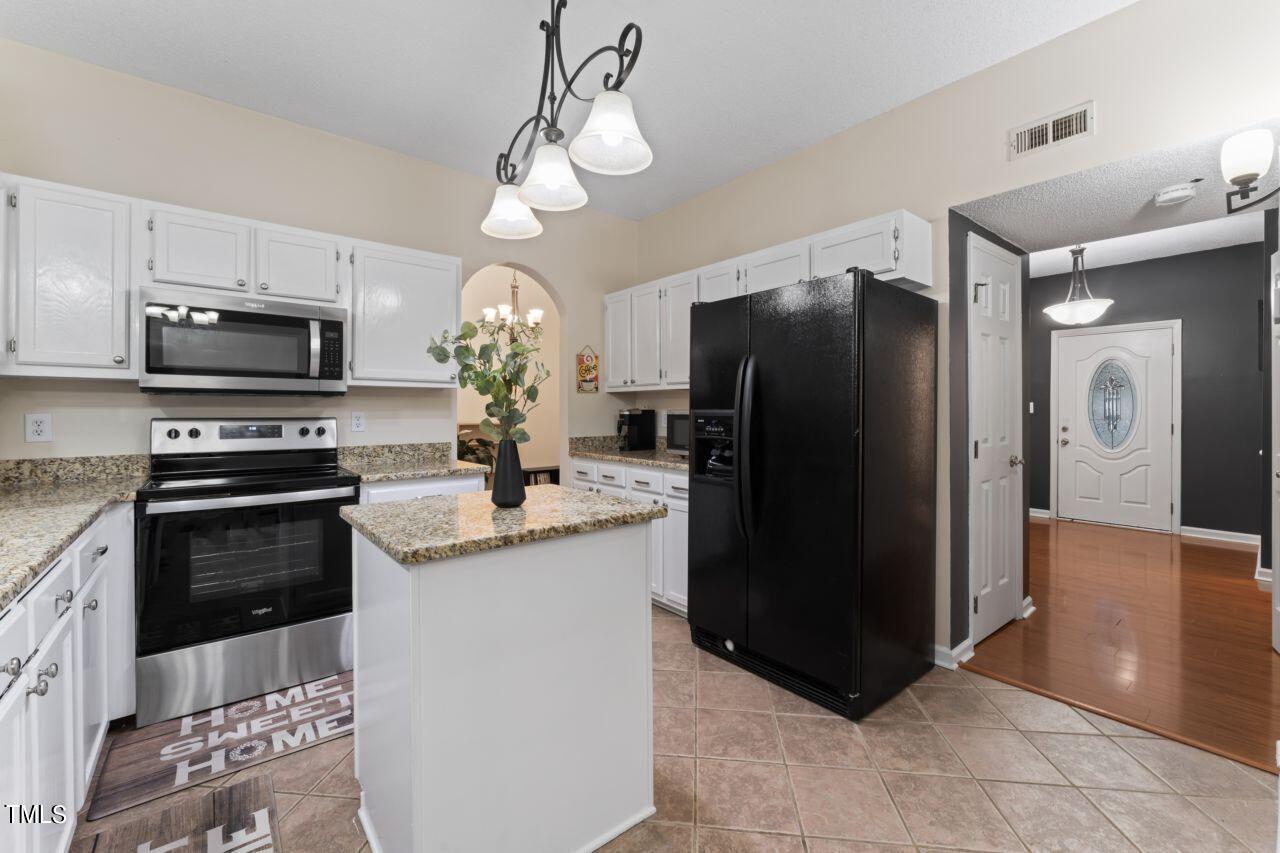 12129 Mabledon Court Raleigh, NC 27613 - Photo 14 of 31 a kitchen with stainless steel appliances granite countertop a refrigerator a stove a microwave and island