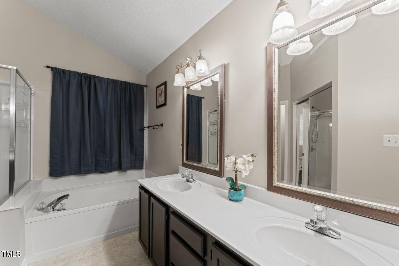 12129 Mabledon Court Raleigh, NC 27613 - Photo 21 of 31 a bathroom with a sink double vanity granite tub shower and a mirror